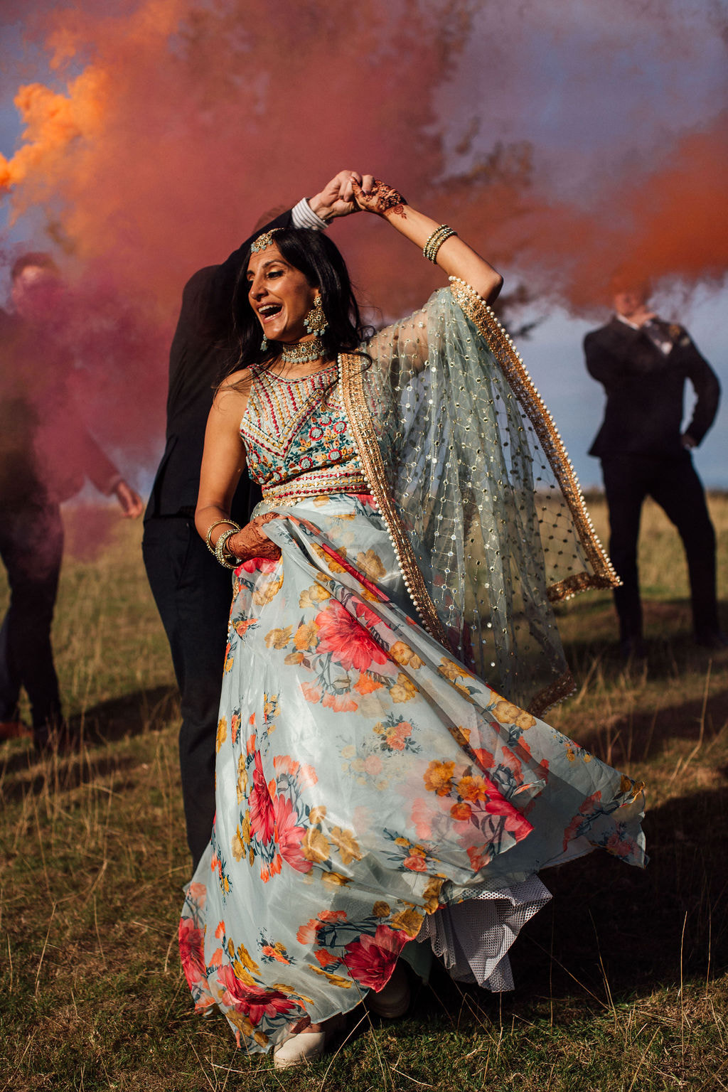 Dancing indian bride with colourful smoke bombs and bright wedding sari