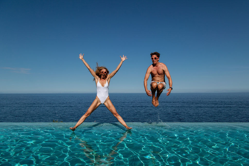 Couple jumping into an infinity pool
