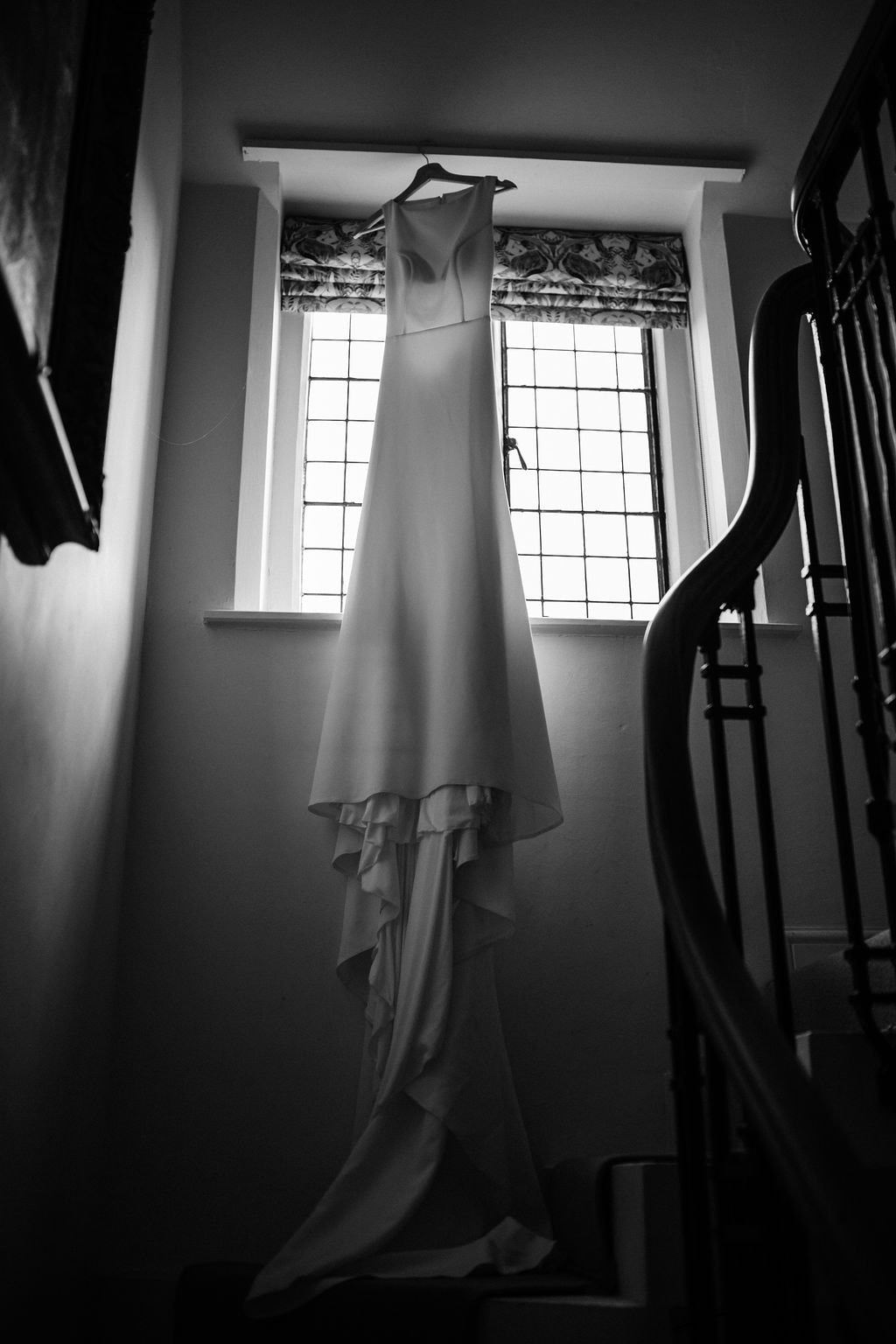 Elegant wedding dress hanging in beautiful window light